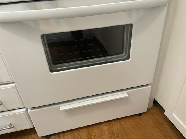 White oven with glass door and drawer, set in a kitchen.