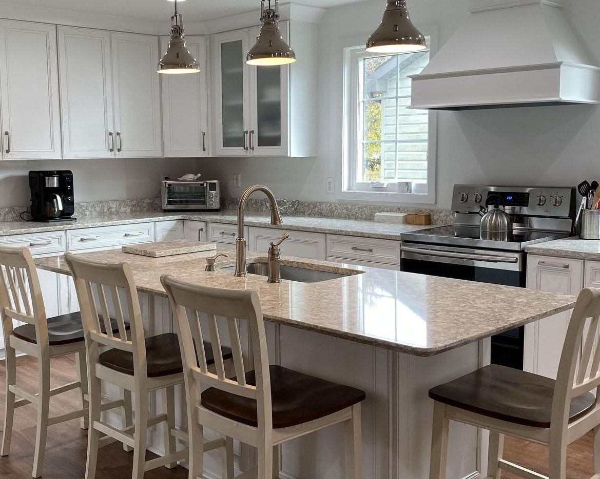 Bright white kitchen with island seating, white cabinets, granite countertops, and stainless steel appliances.