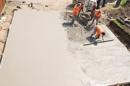 A group of construction workers are working on a concrete floor.