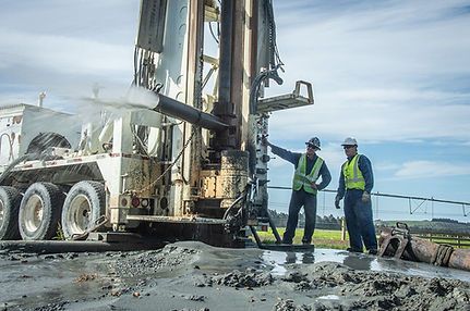 Two men are standing in front of a large machine.