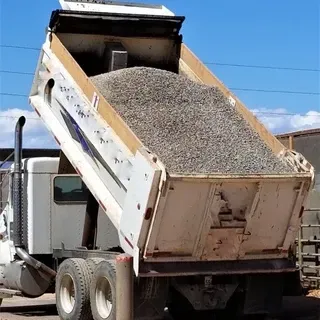 A dump truck is loaded with gravel and the back of the truck is open
