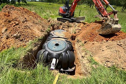An excavator is digging a hole for a septic tank.
