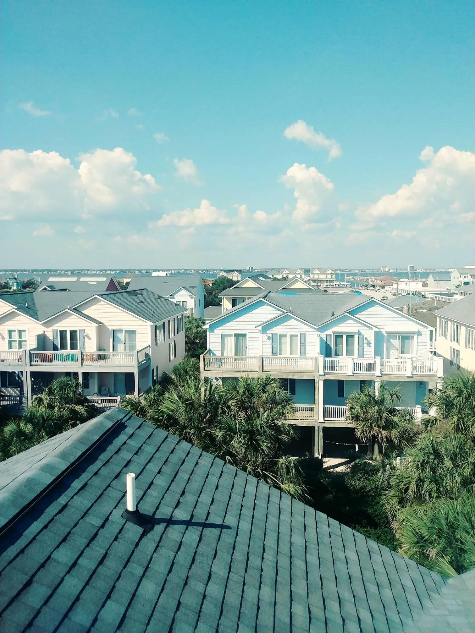 Houses under a bright blue sky with scattered clouds.