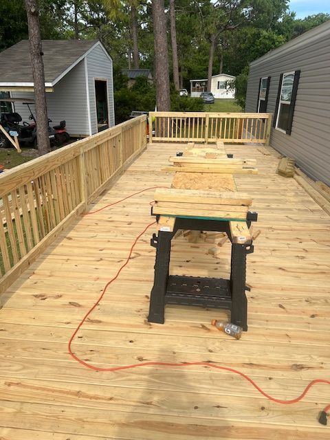 Newly built wooden deck with a sawhorse and tools, near a house.