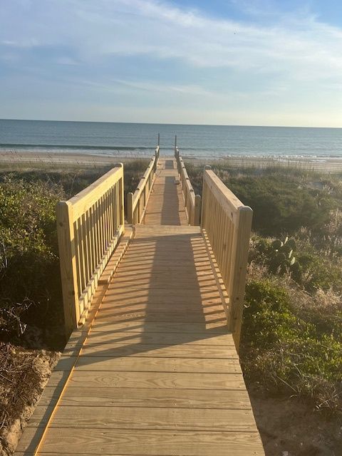 Wooden boardwalk leading to the beach and ocean on a sunny day.