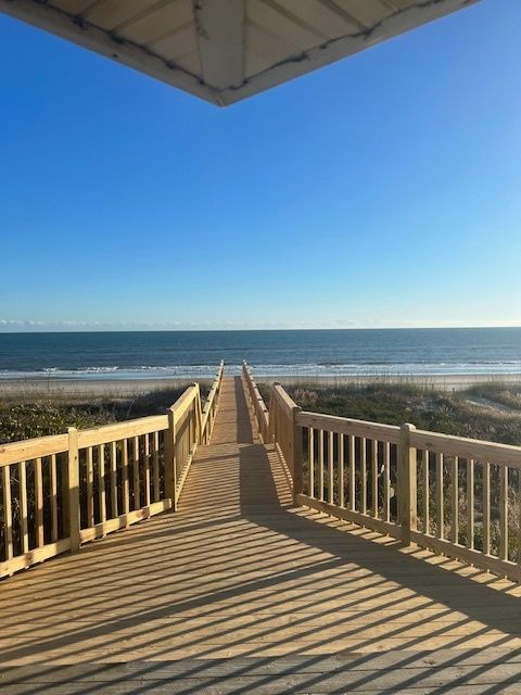 Wooden boardwalk leading to the ocean under a clear blue sky.