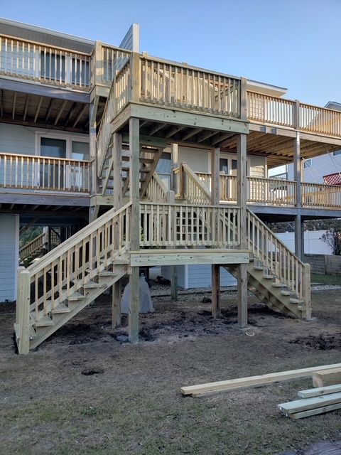 Wooden staircase and deck connecting two-story building, exterior shot.