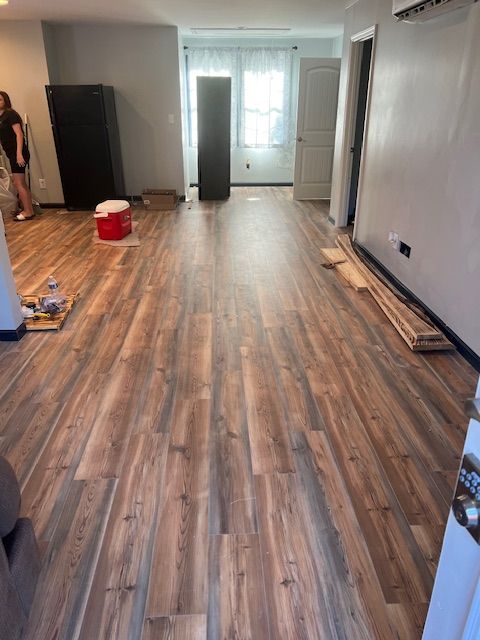 New wood-look flooring installed in a room; appliances and a person are present.
