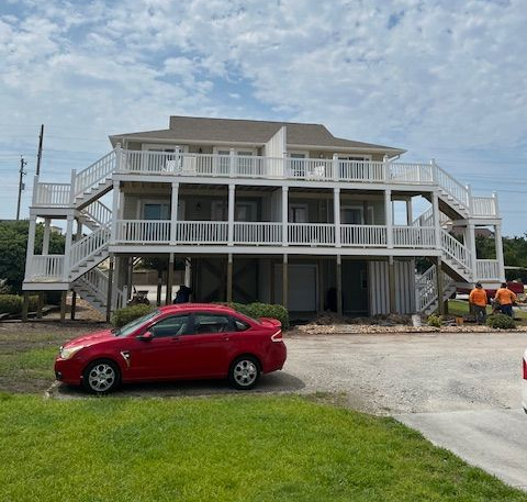 Roofing crew installing shingles on a residential roof, sunny day, blue shirts, working in tandem.
