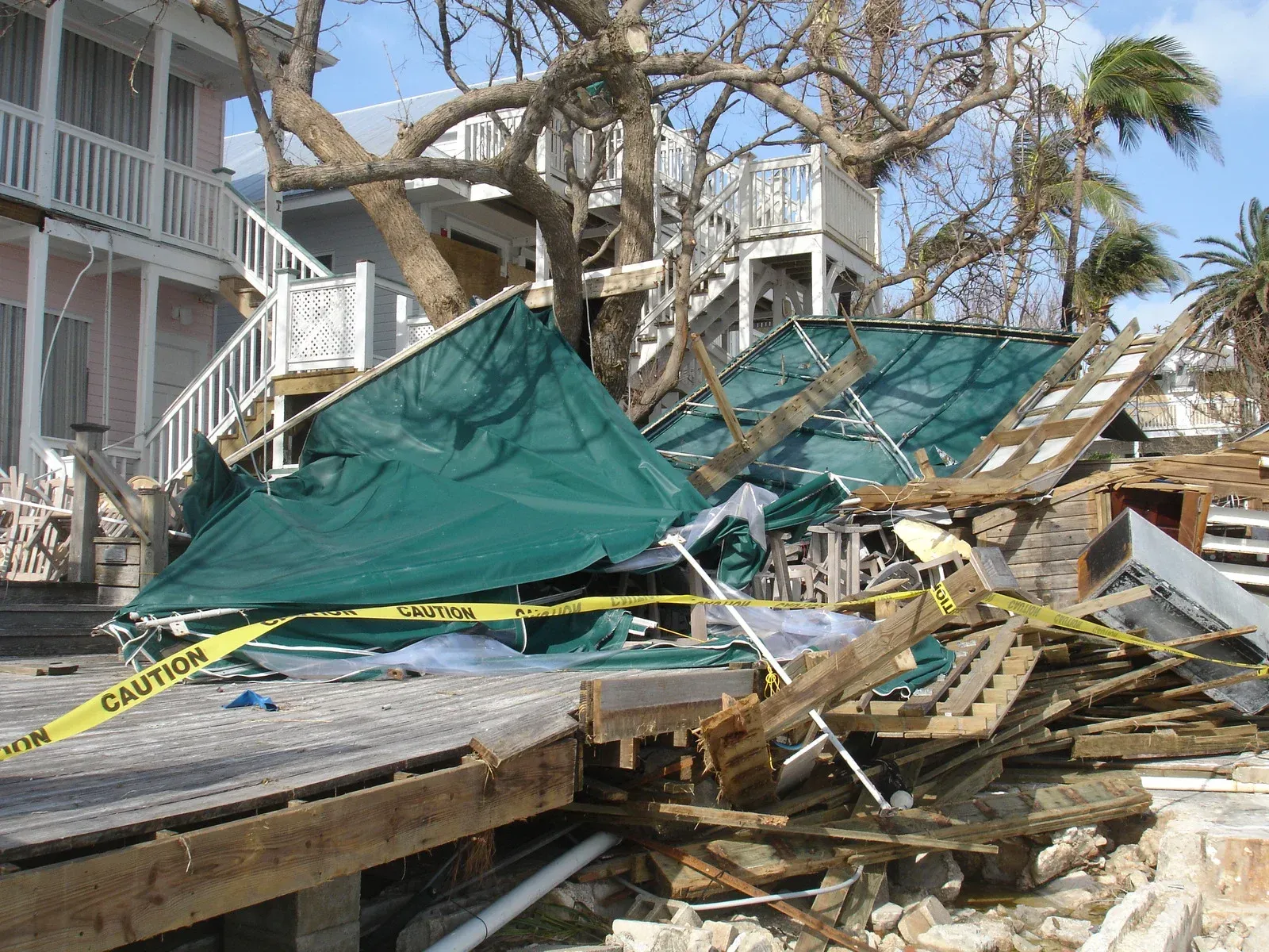 Hurricane damage: Collapsed roof, debris, caution tape near a building.