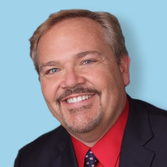 A man in a suit and tie is smiling for the camera