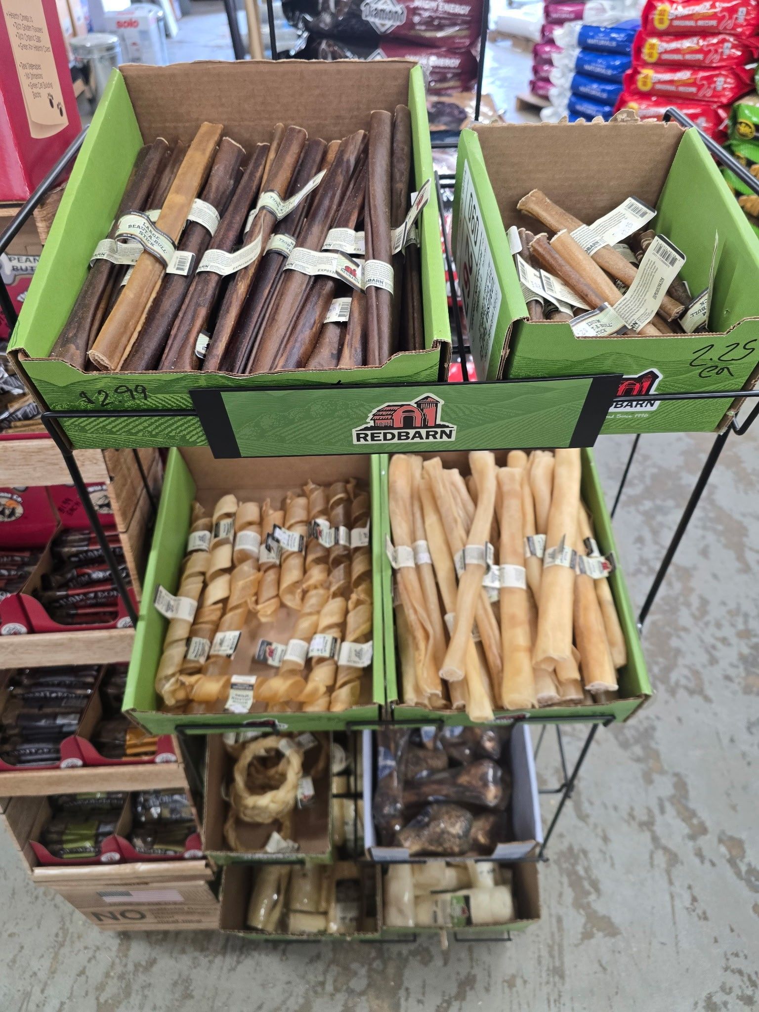 A variety of dog treats are displayed on a shelf in a store.