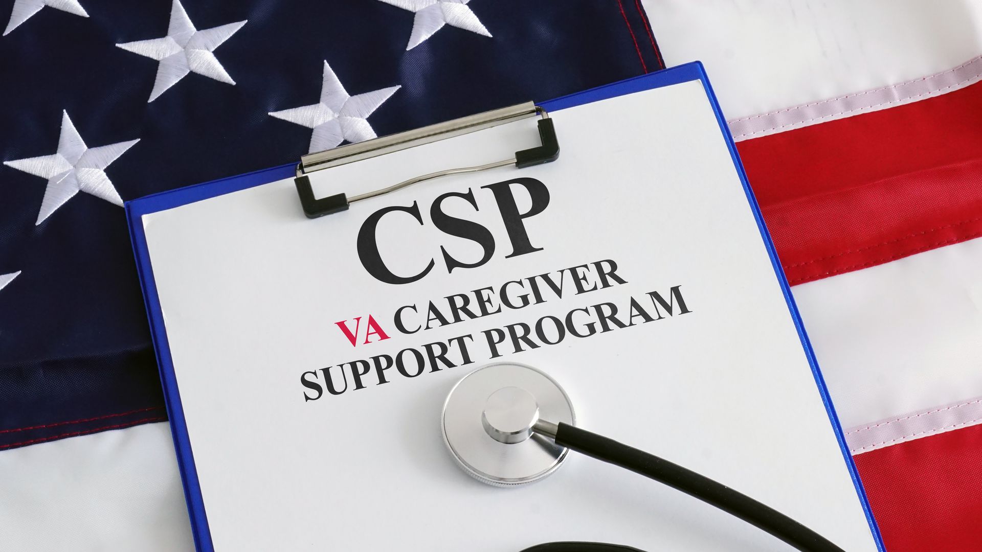 A clipboard with a stethoscope on top of a United States flag 