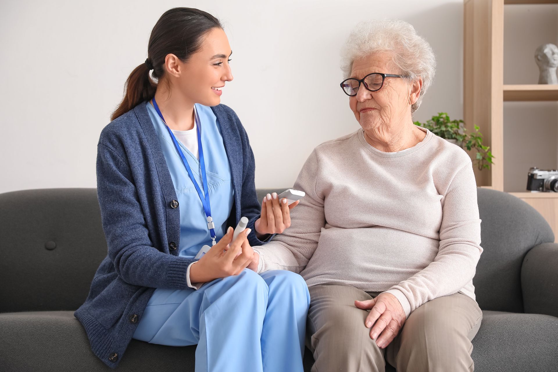 In-home diabetic care giver measuring sugar level of senior woman at home