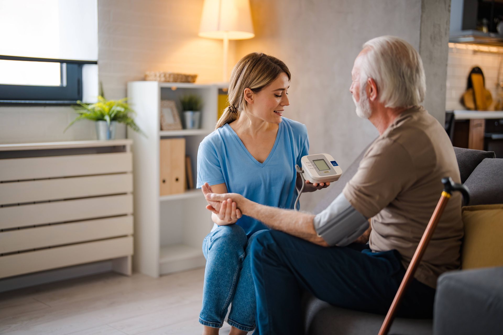 A caregiver assisting an elderly man in his home with a blood pressure monitor near Lexington, Kentucky