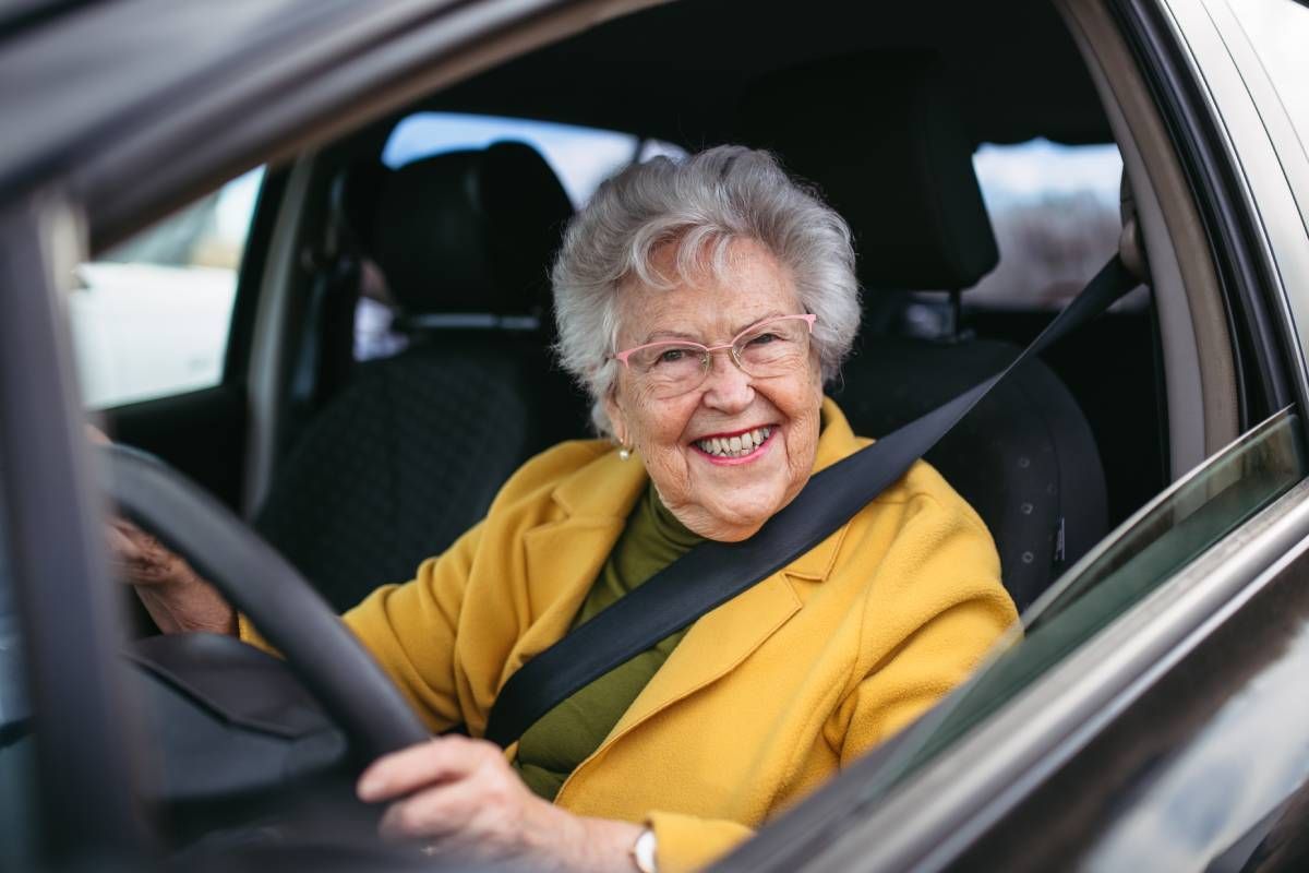 A Senior Lady sitting behind the wheel of a car, smiling widely at Family Choice Home Care near Lexington, KY