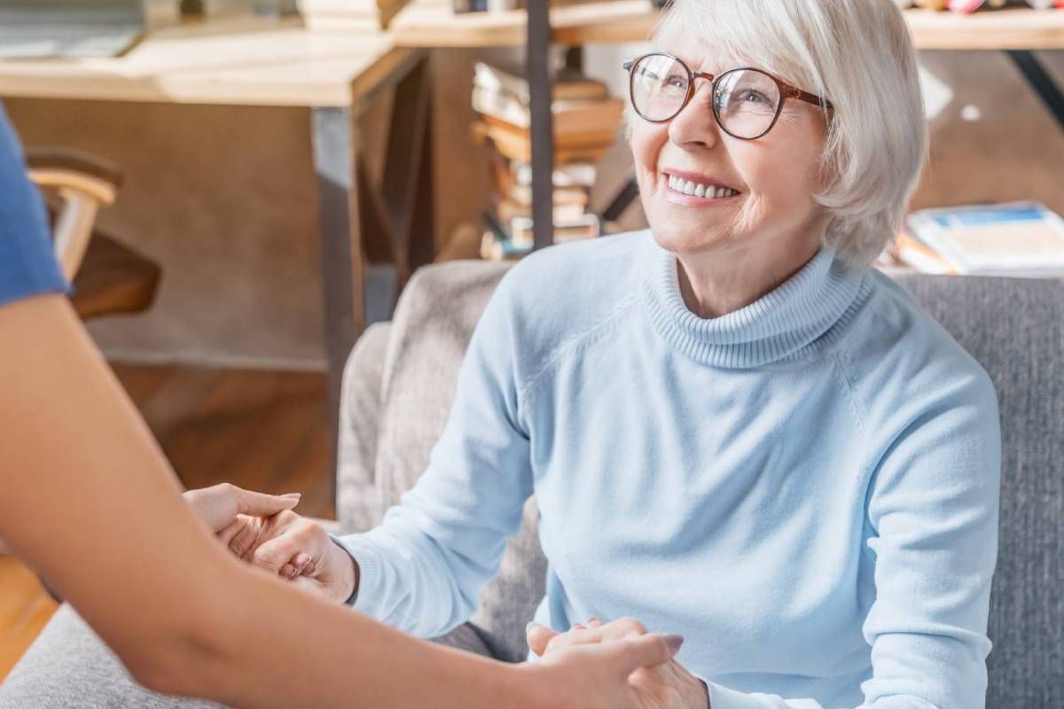 Nurse helping a smiling elderly woman stand up from a seat at Family Choice Home Care near Lexington, KY