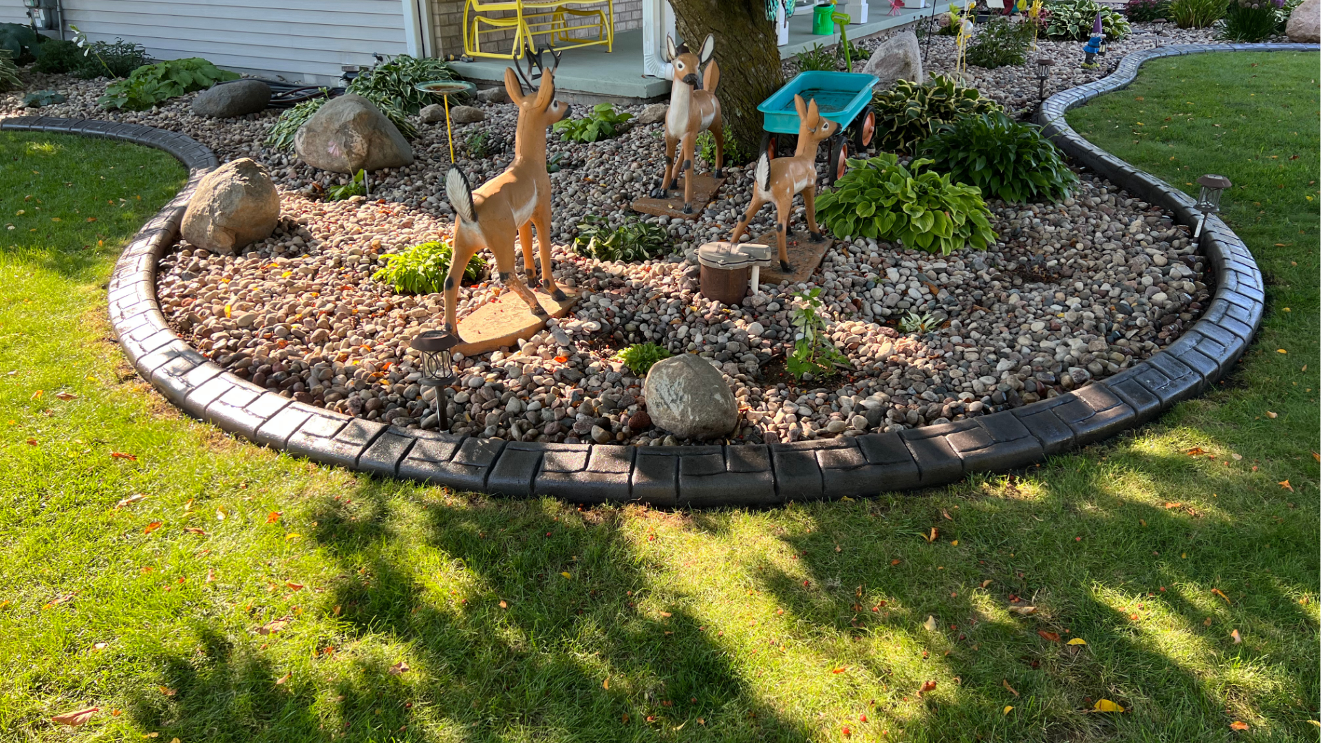 A garden with a deer statue in the middle of it.