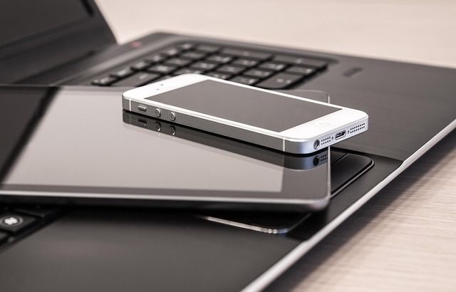 Smartphone resting on a tablet and laptop keyboard on a desk