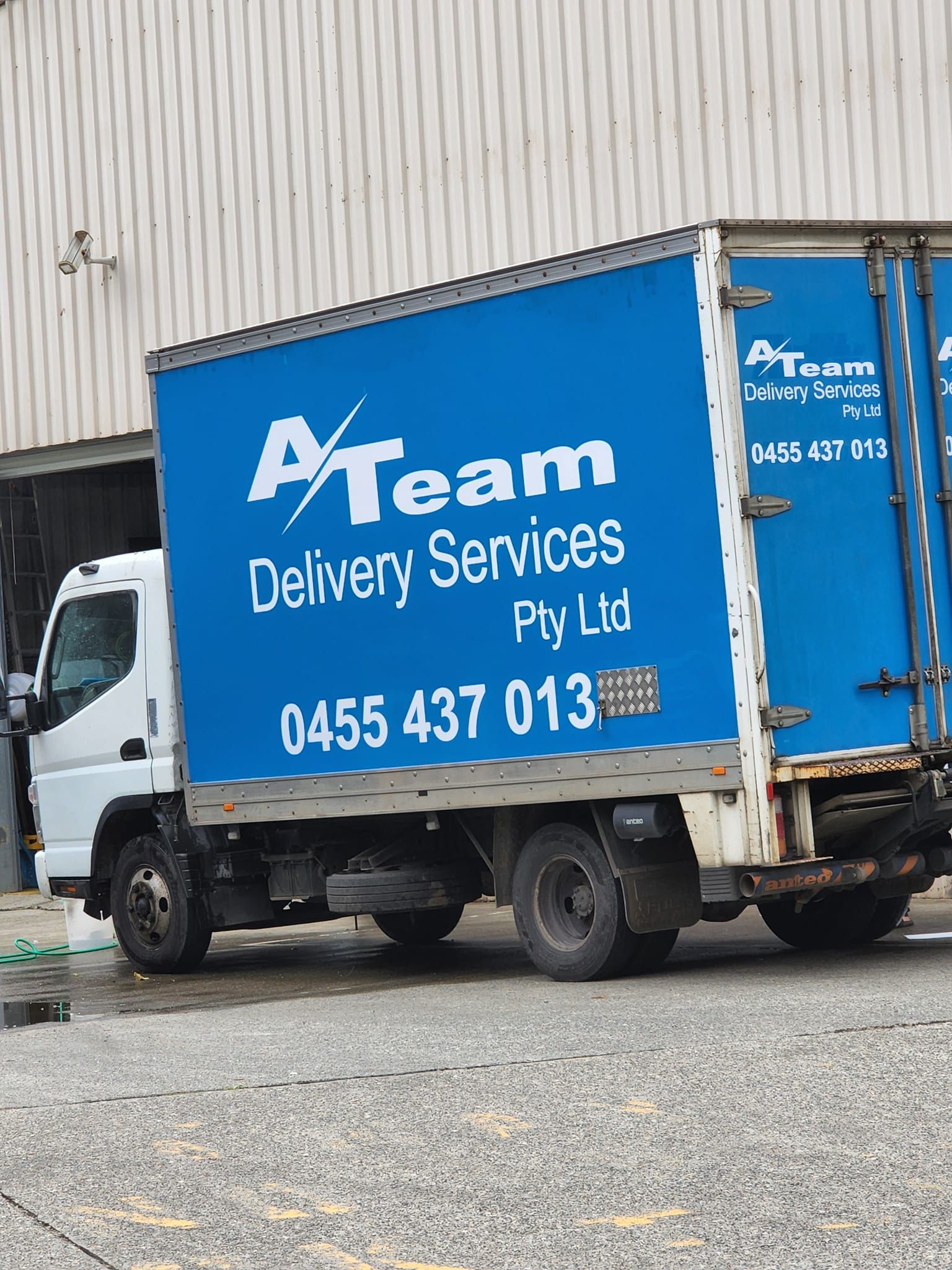A Blue and White Delivery Truck is Parked in Front of a Building — A-Team Delivery Services Pty Ltd in Cessnock, NSW