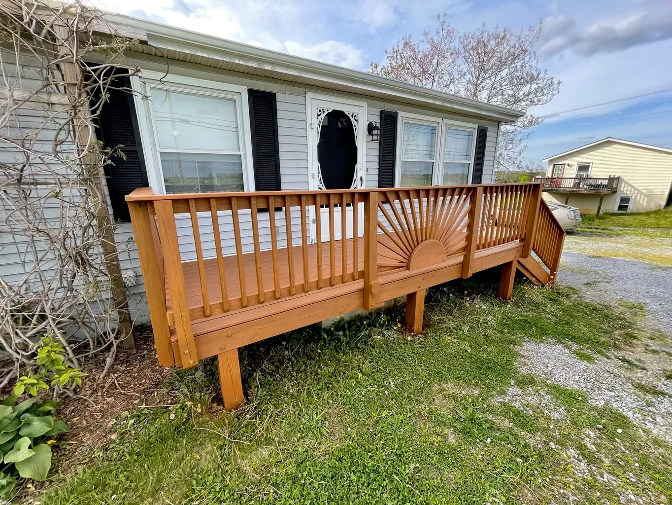 A mobile home with a wooden deck and stairs in front of it.