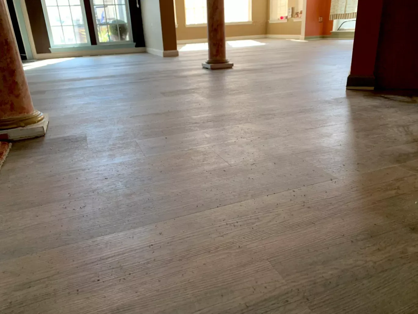 A large room with a wooden floor and columns.