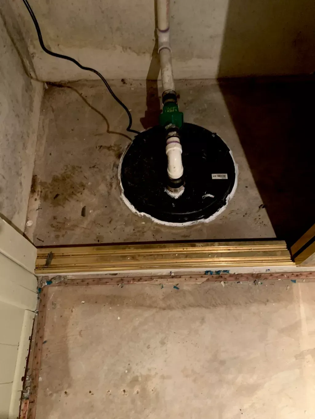 A basement pump is sitting on the floor next to a door.