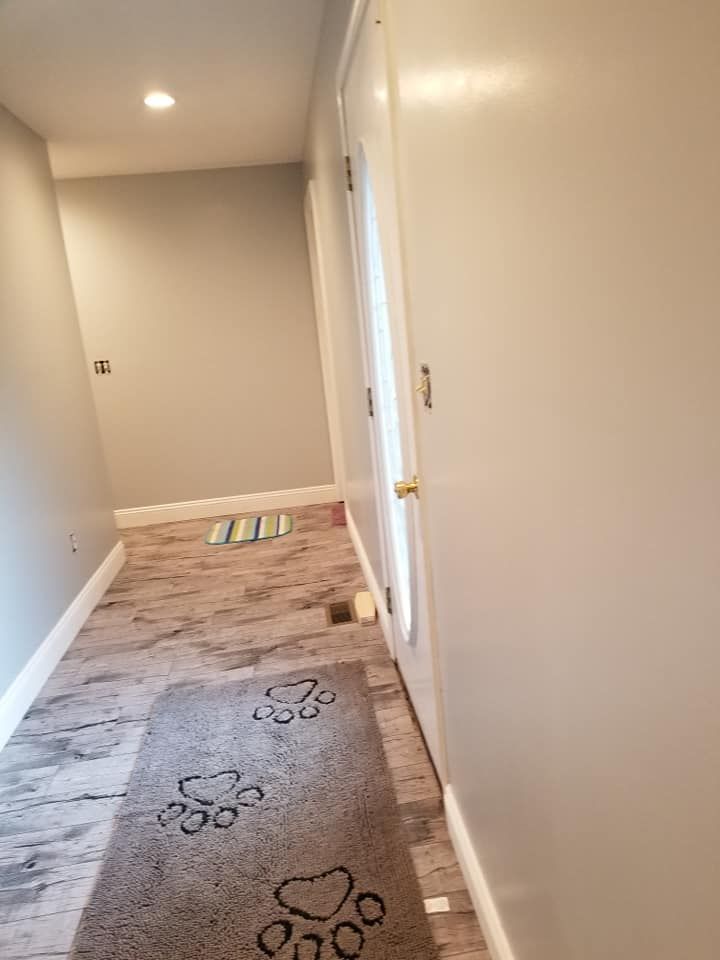 A hallway with a rug on the floor and a door.