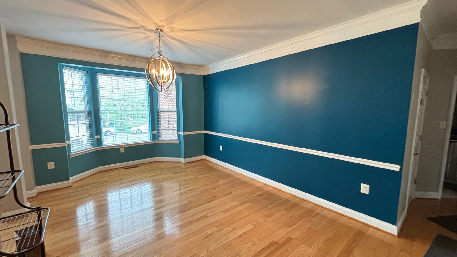 An empty living room with blue walls and hardwood floors.