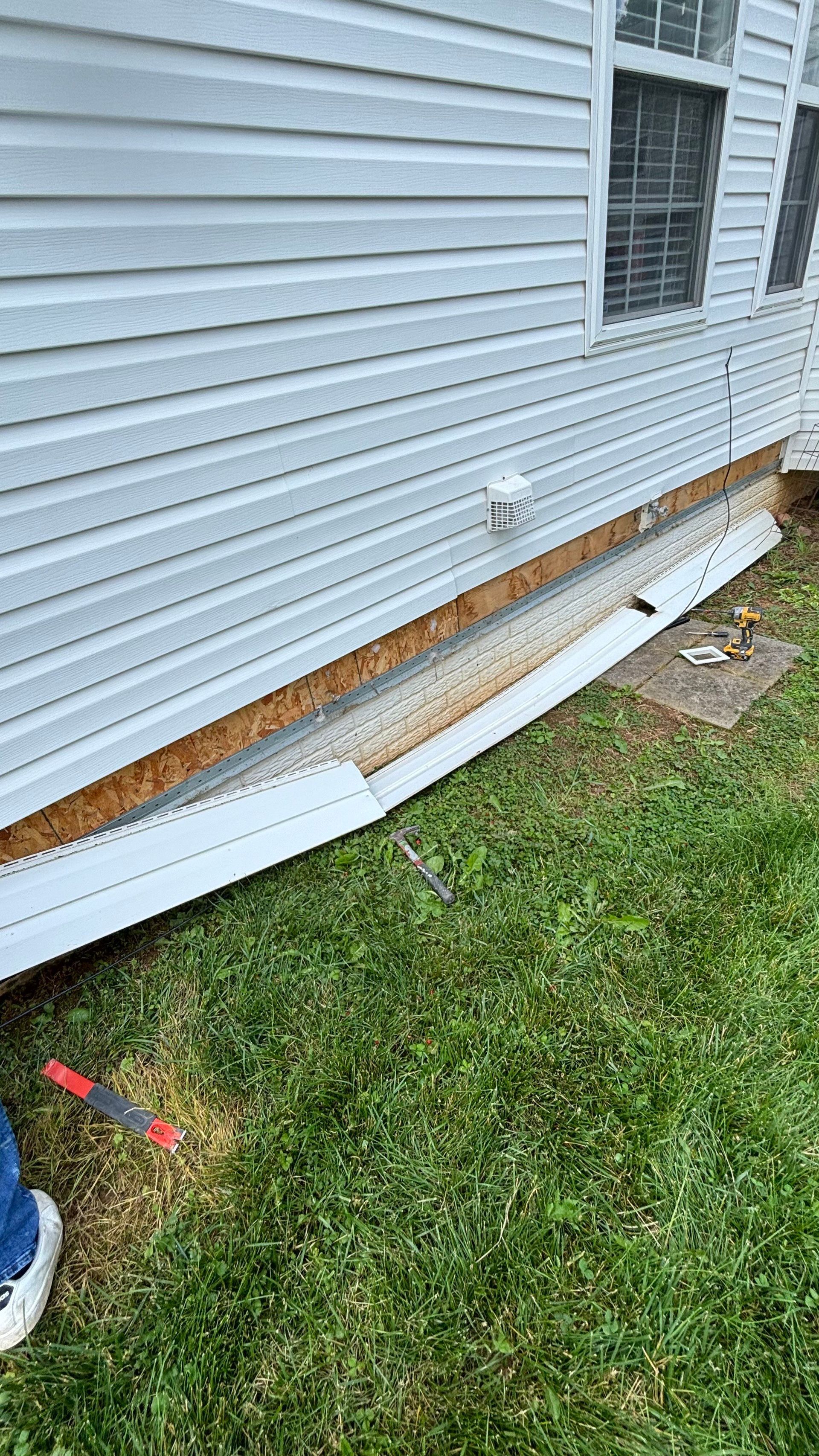 A white house is sitting on top of a lush green lawn.