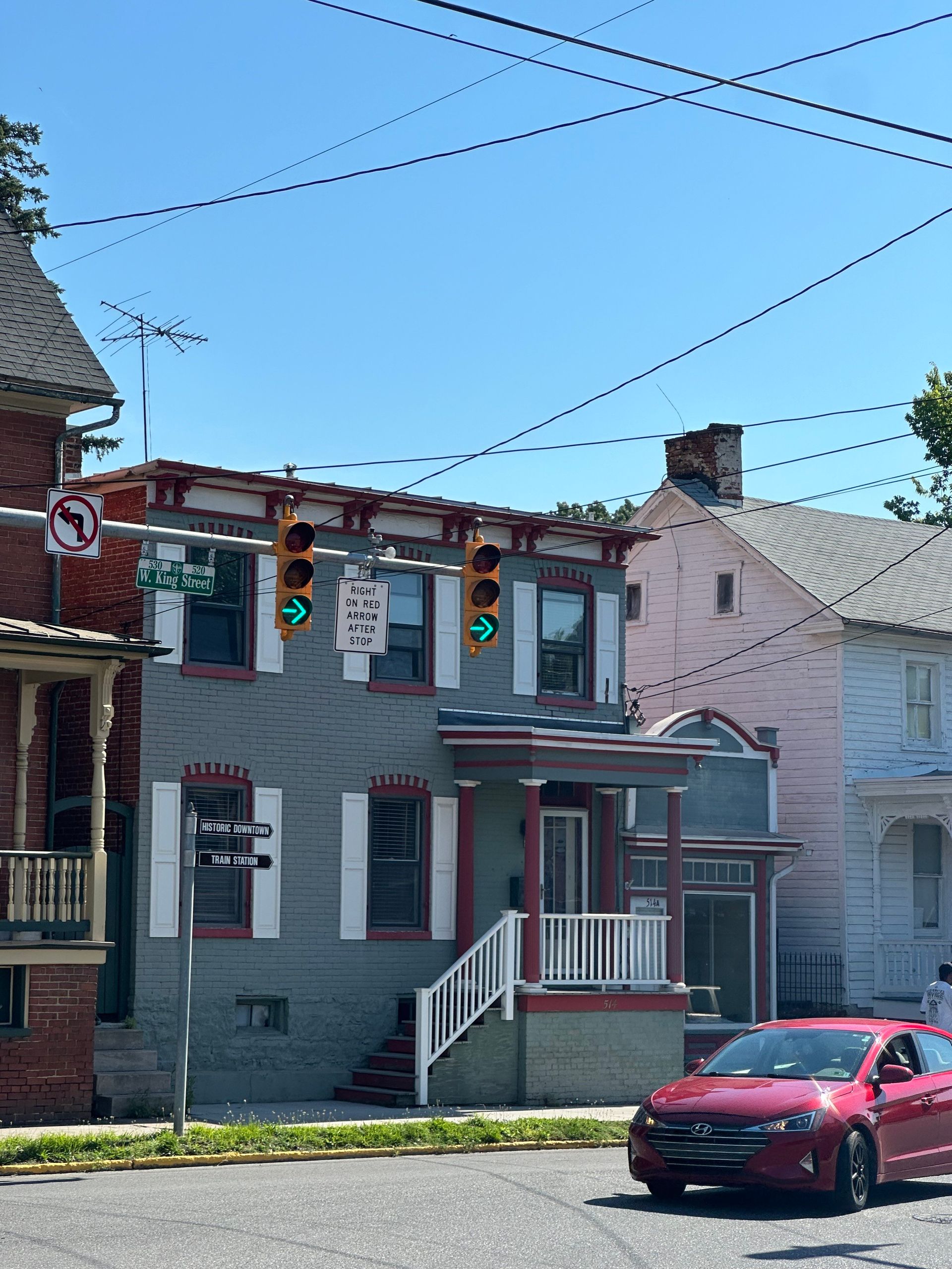A red car is parked in front of a brick building