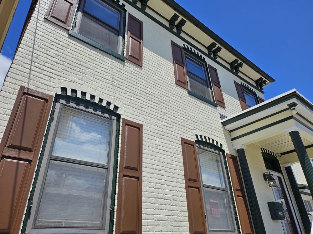A white brick building with brown shutters on the windows