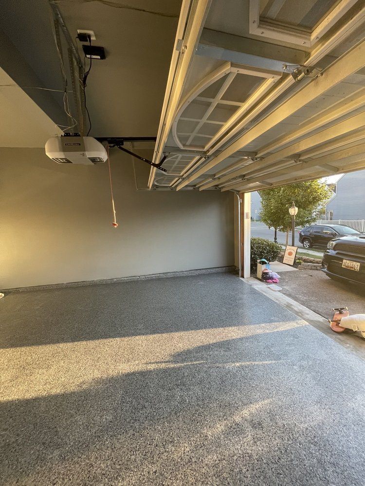 An empty garage with a car parked in the driveway.