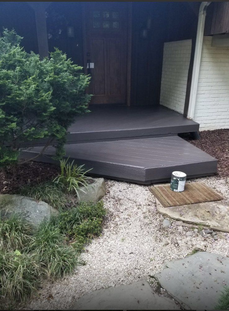A bucket of paint is sitting on a mat in front of a house.