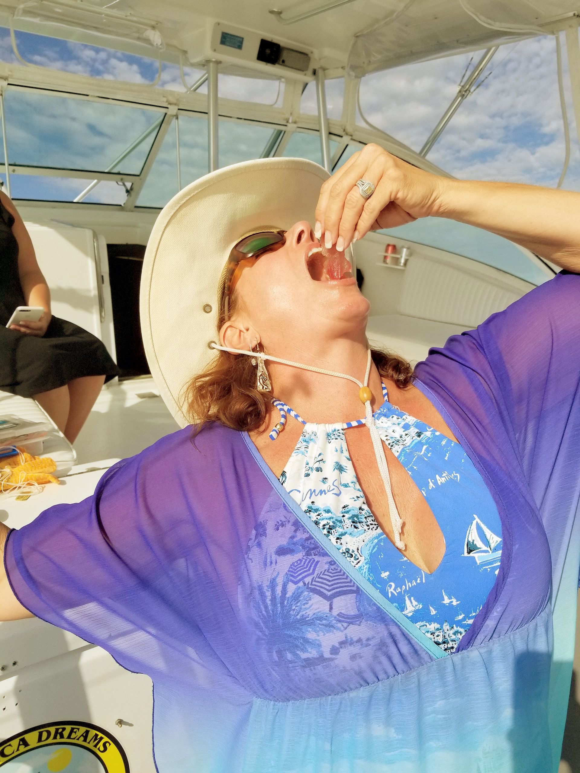 A woman wearing a hat and sunglasses is sitting on a boat