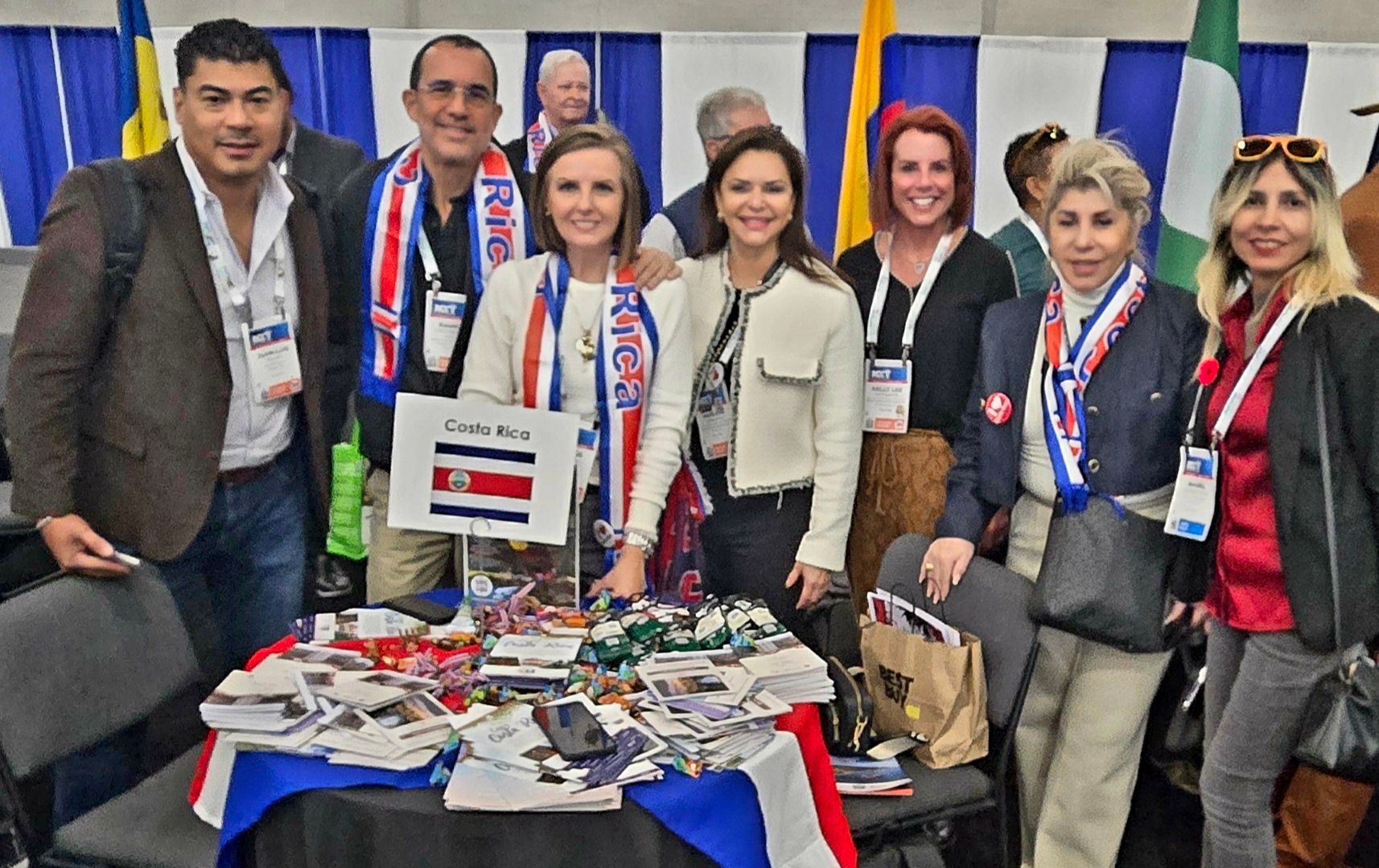 A group of people are posing for a picture in front of a table with a sign that says ' costa rica ' on it