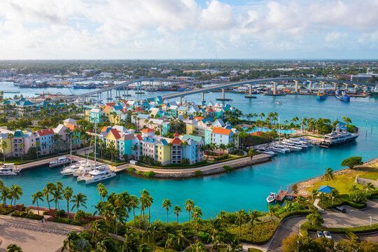 An aerial view of a small island in the middle of a body of water surrounded by buildings and palm trees.