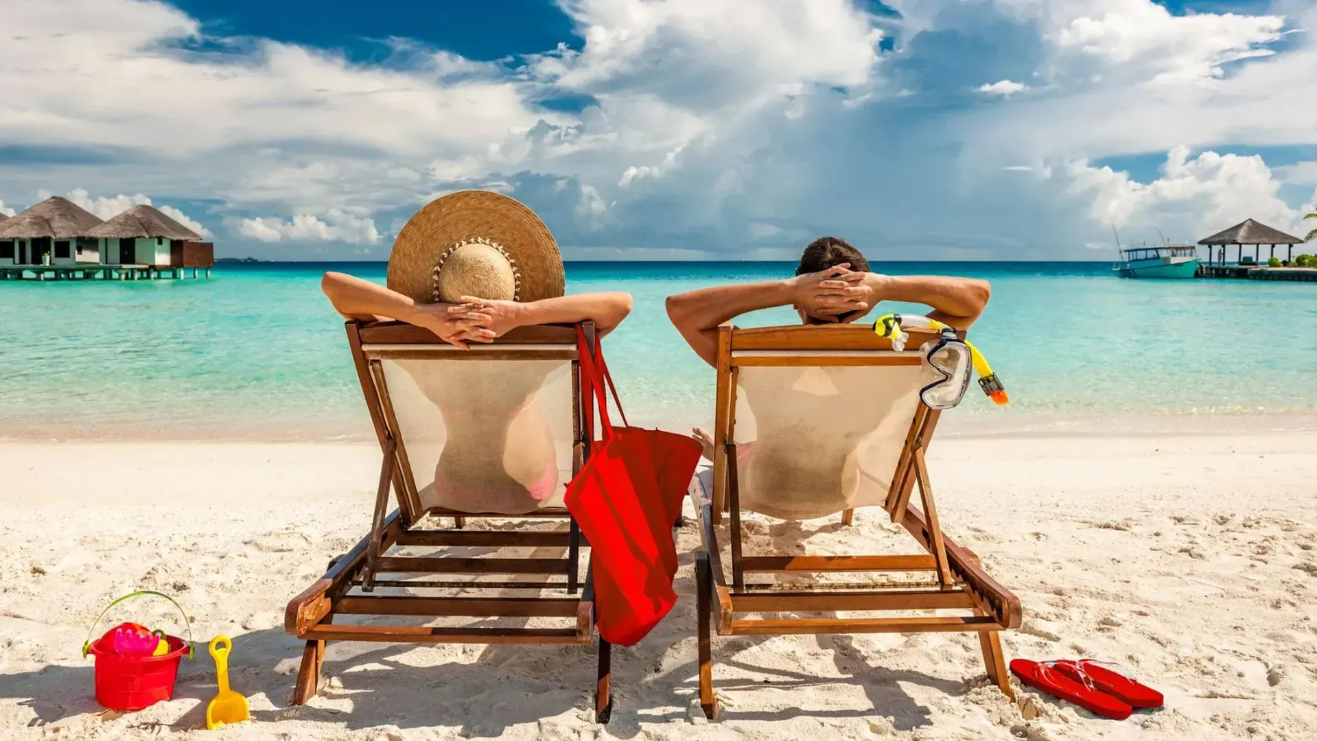 A man and a woman are sitting in lawn chairs on a beach.