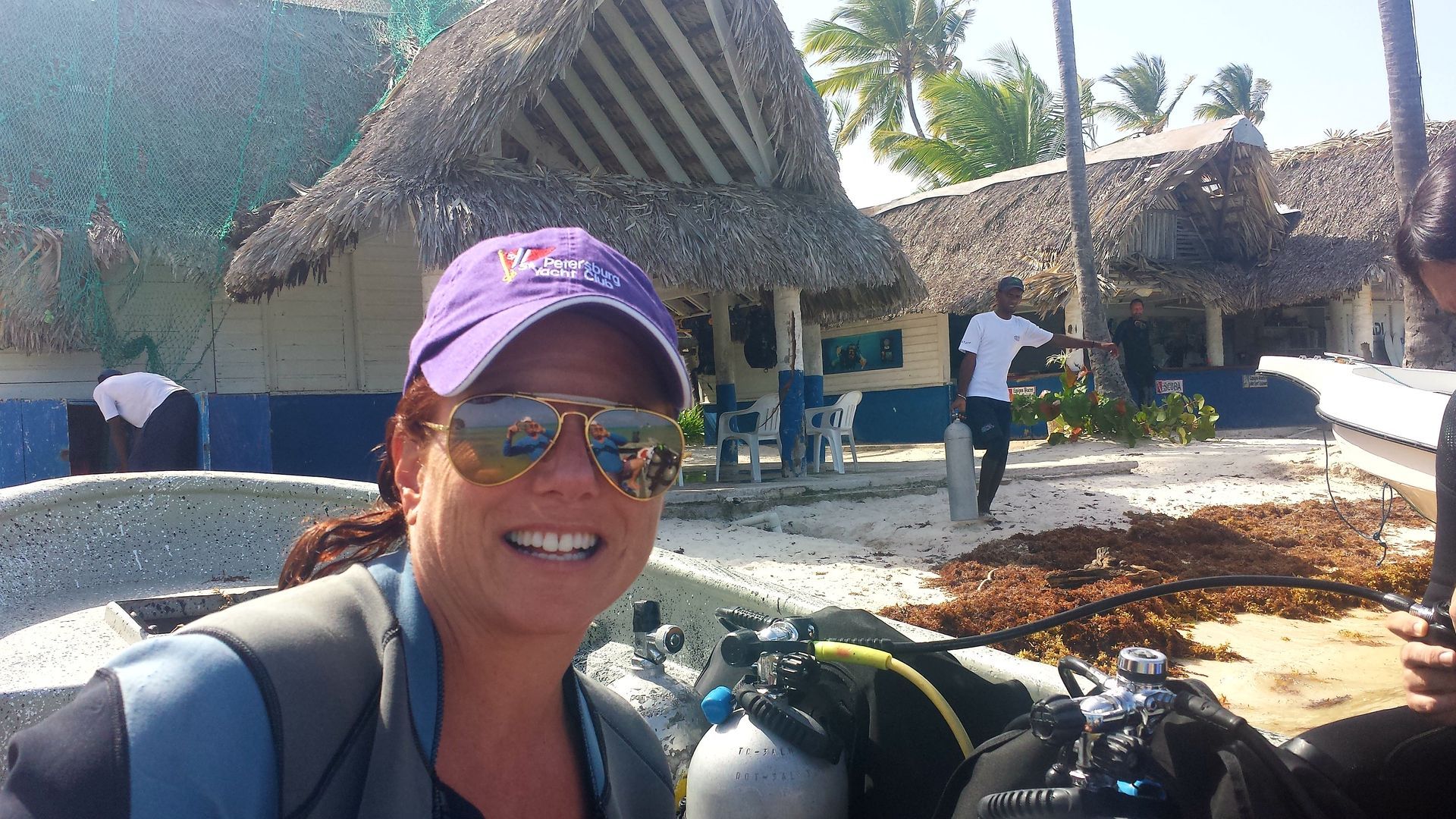 A woman wearing a purple hat and sunglasses is smiling