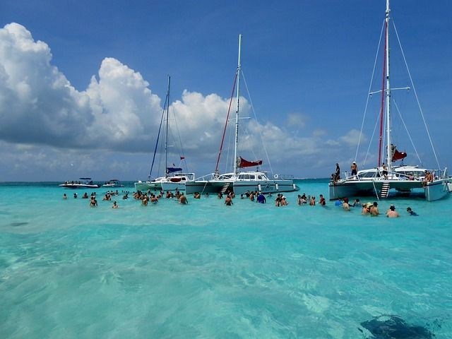 A group of people are swimming in the ocean near boats.