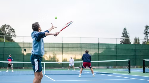 A man is hitting a tennis ball with a racket on a tennis court.