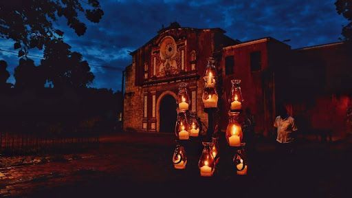 A group of candles are lit up in front of a building at night.