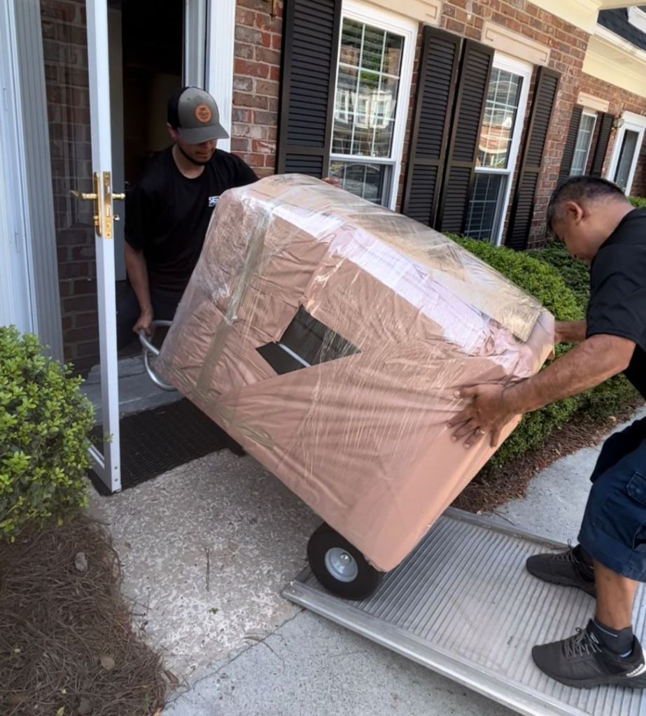 Two men are carrying a large box on a dolly.