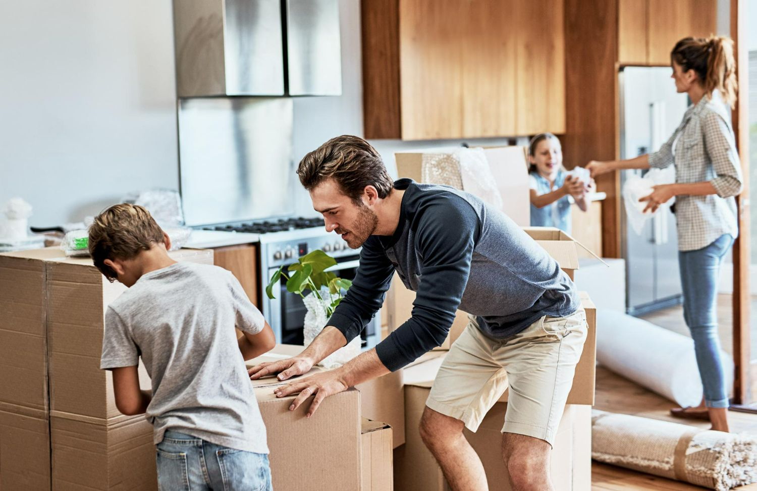 Family unpacking cardboard boxes in a bright living room during a move
