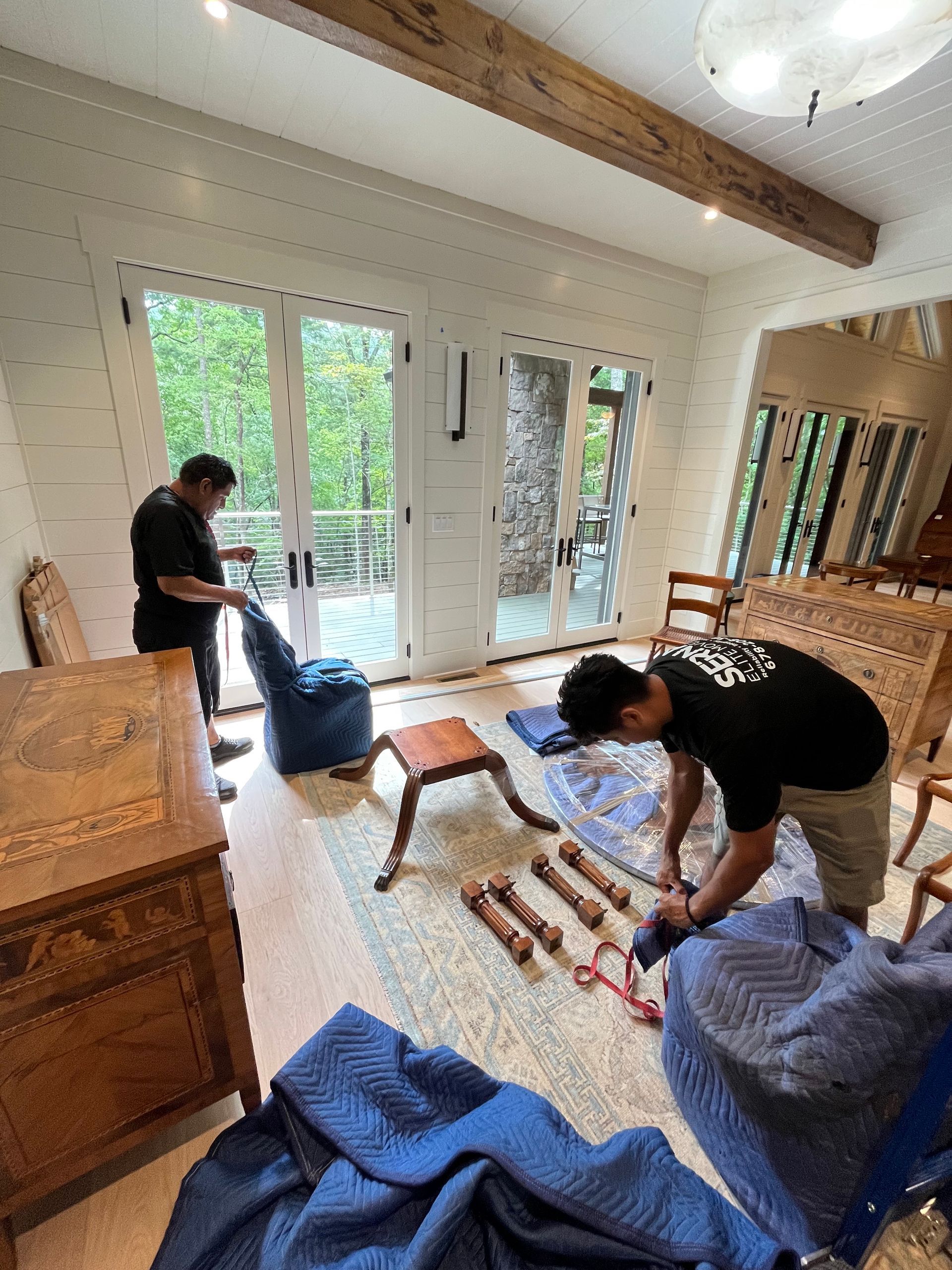 Two men are moving furniture in a living room.