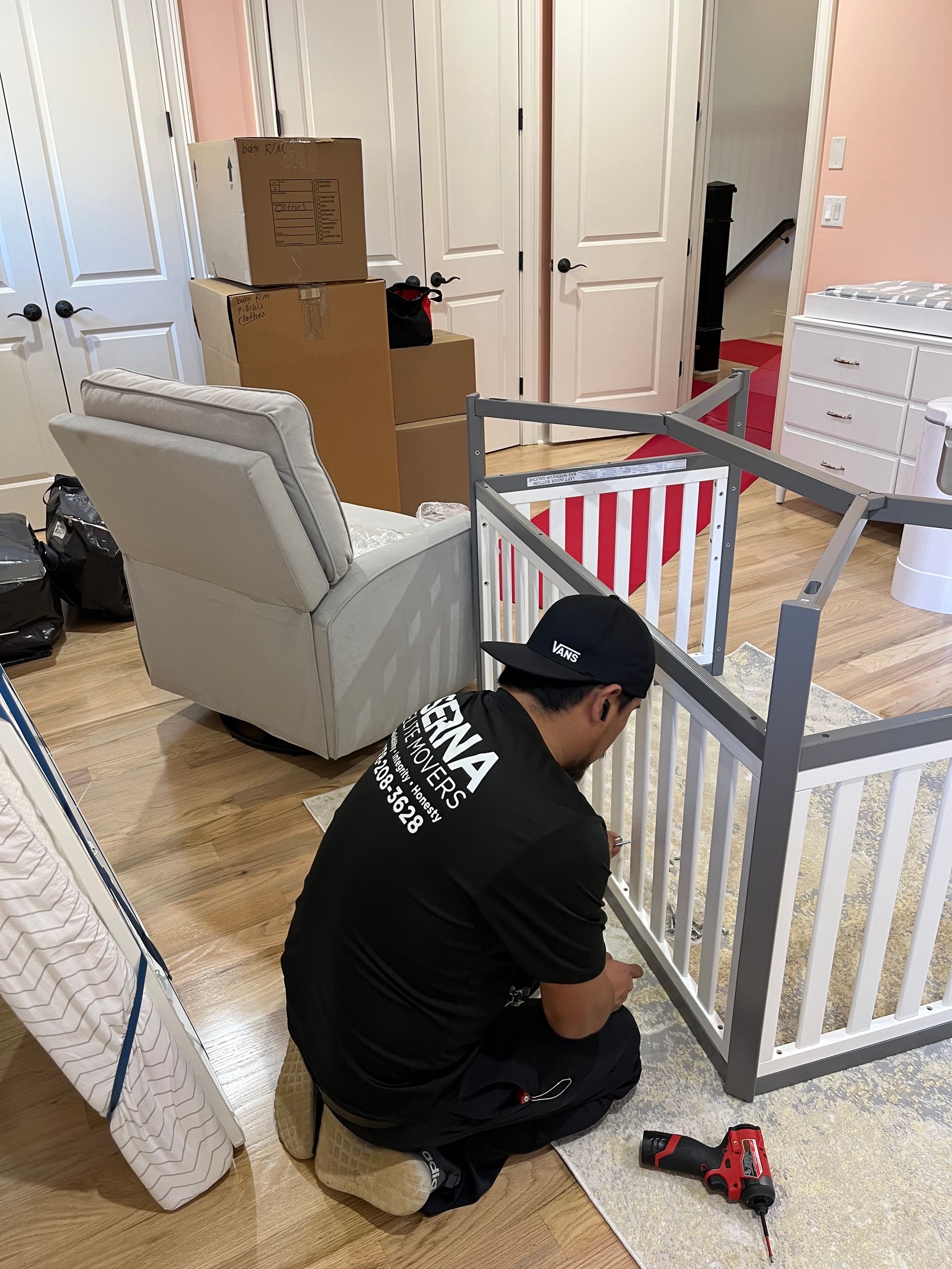 A man is working on a crib in a living room.