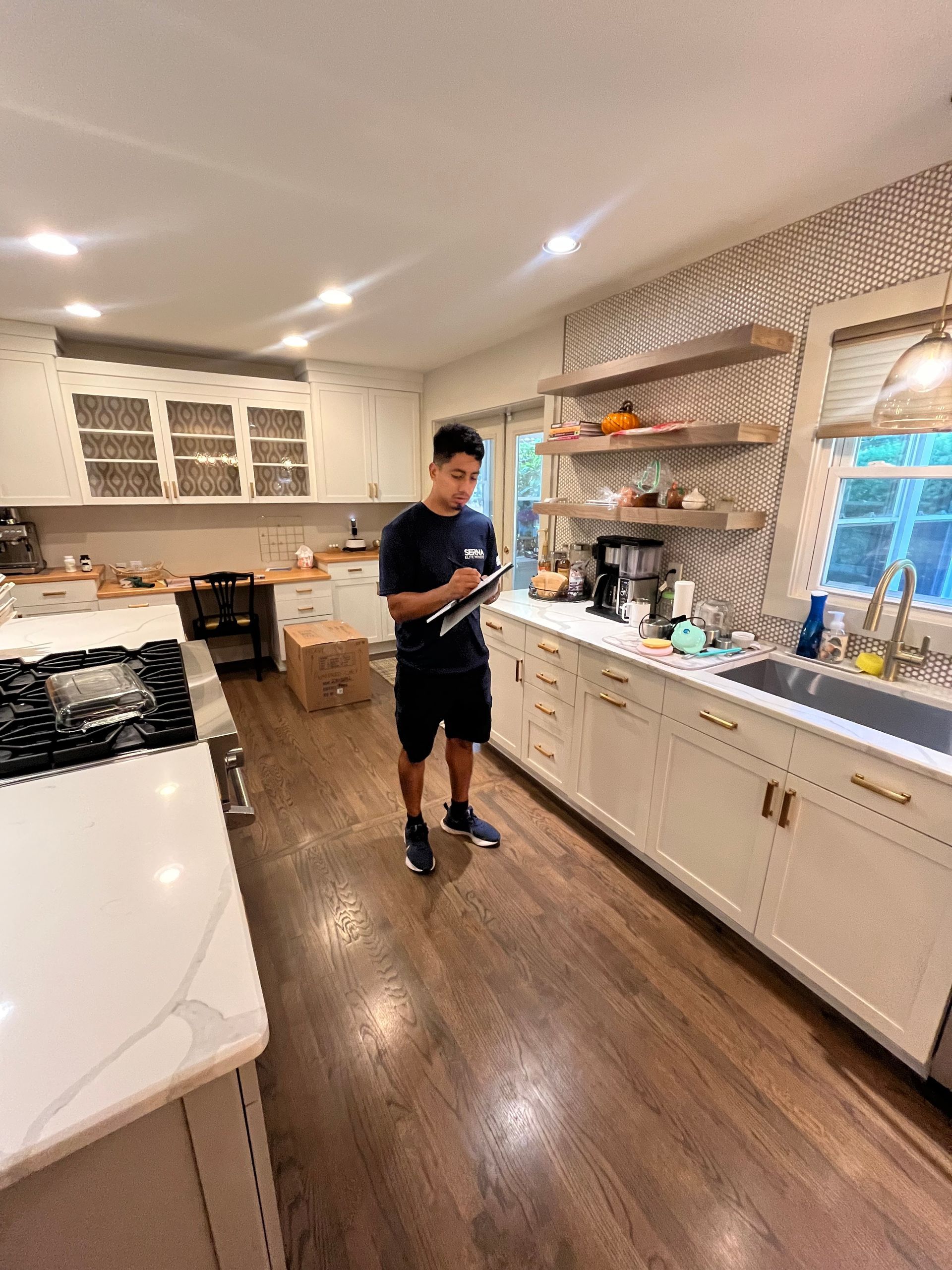 A man is standing in a kitchen looking at a tablet.