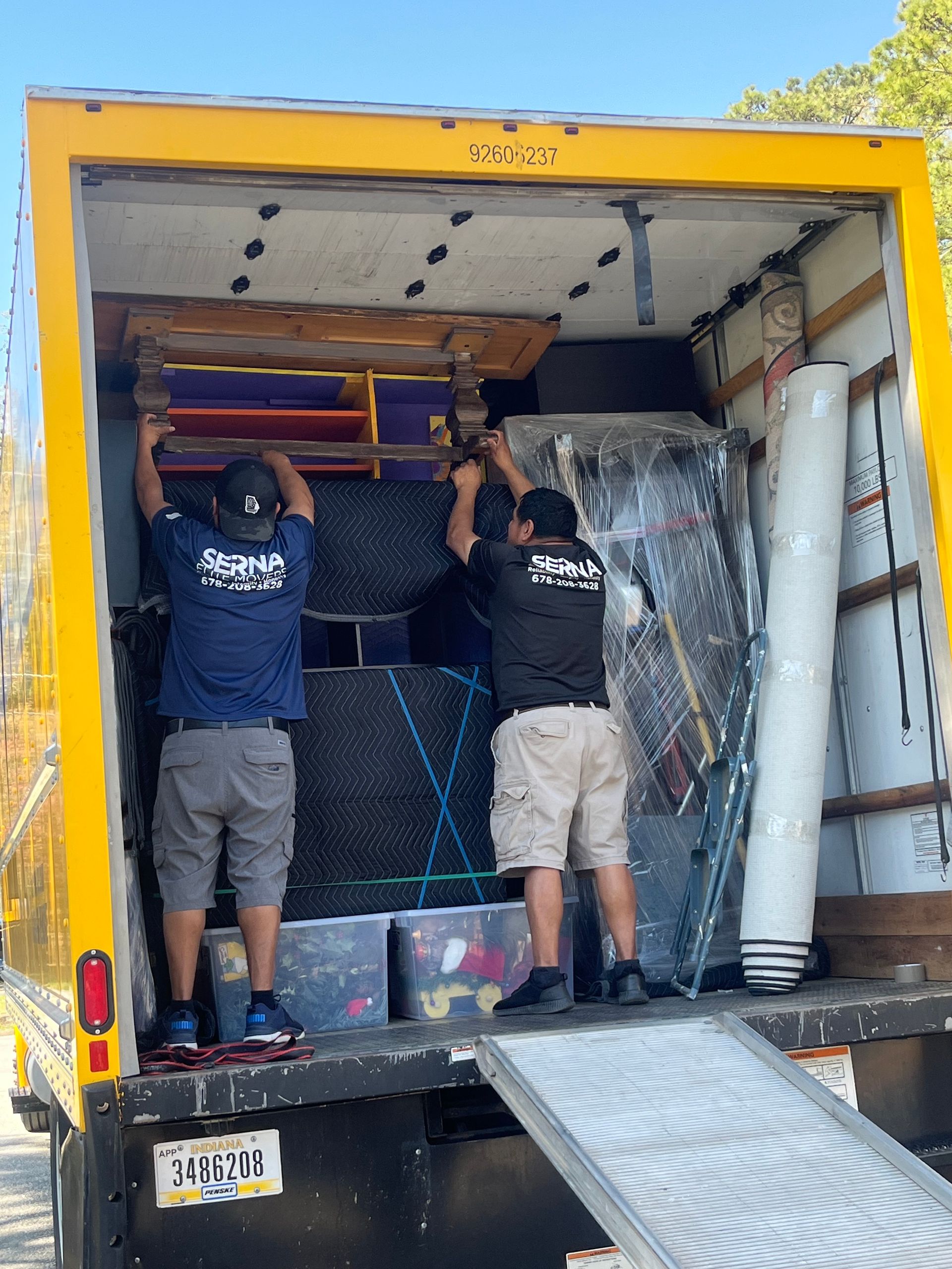 Two men are loading furniture into a moving truck.