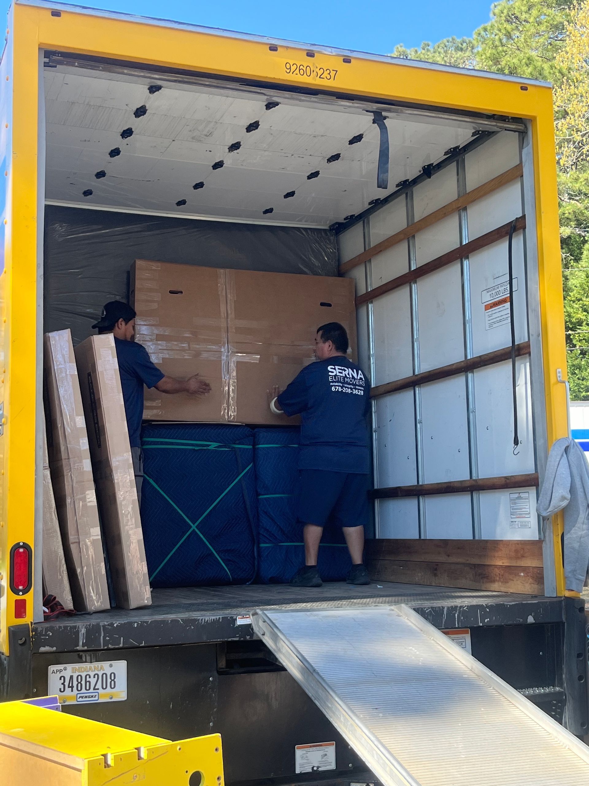 Two men are loading a large box into a moving truck
