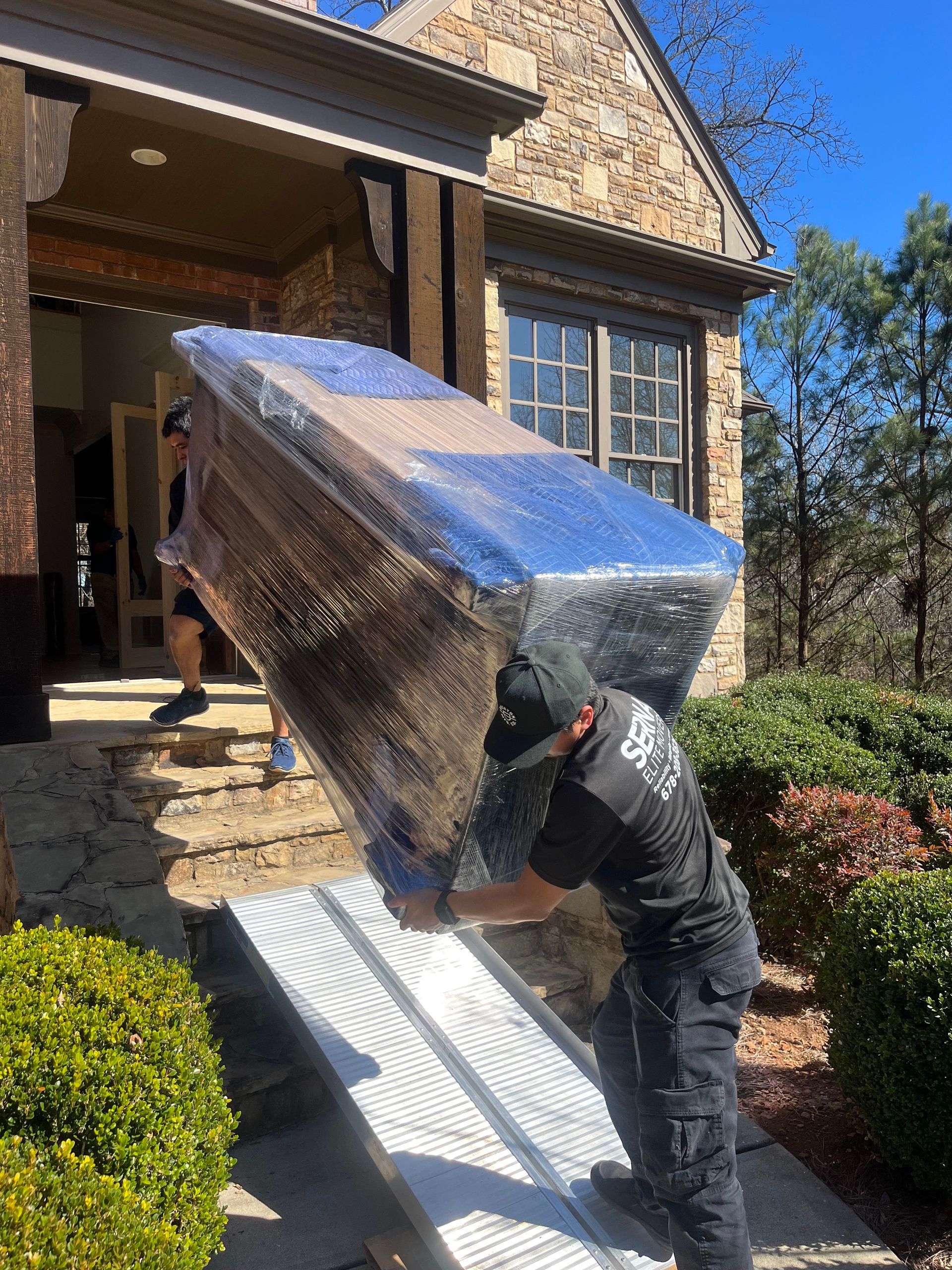 A man is carrying a large piece of furniture on a ramp.
